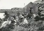 Bild från expedition i Antarktisområdet. Motiv av en grupp med män, kvinnor och barn utanför ett litet trähus, 1912.