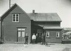 Bild från expedition i Antarktisområdet. Motiv av fyra män och hund utanför hus (New Island Station) på Falklandsöarna.