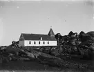 Fotografi från Grönland. Motiv av en kyrka och hus i ett bergslandskap.