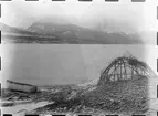 Fotografi från Eldslandet. Motiv av kanot på strand med berg i bakgrunden.