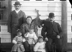 Fotografi från Eldslandet. Motiv av familj framför hus.