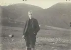 Fotografi från expedition till Spetsbergen 1920. Motiv av ung man som poserar framför berg.