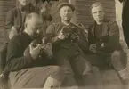 Fotografi från expedition till Spetsbergen 1920. Motiv av fyra män som sitter på trappa och håller i hundvalpar.