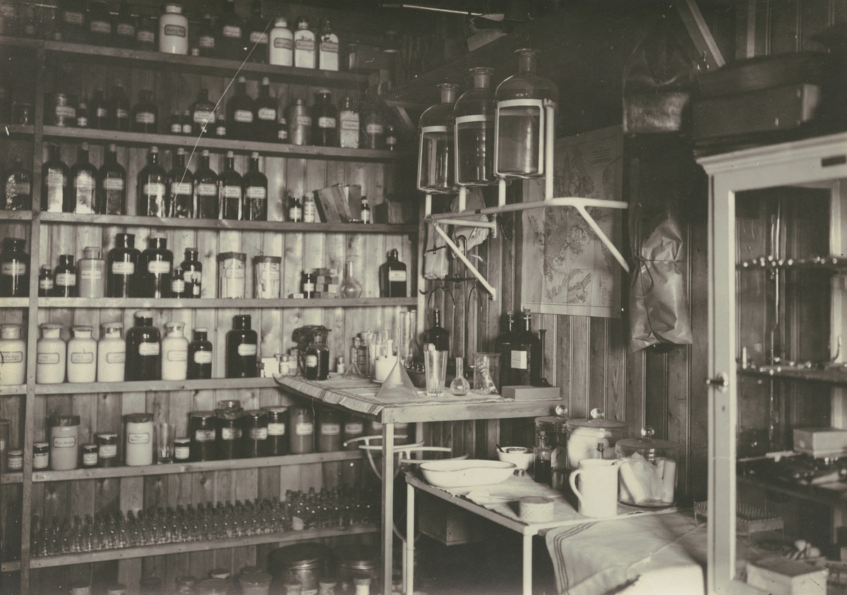 Fotografi från expedition till Spetsbergen 1920. Interiörbild från vad som ser ut att vara en läkarmottagning eller apotek.