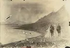 Fotografi från expedition till Spetsbergen 1920. Motiv av två män som står bredvid tält på stenig strand.