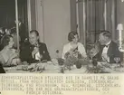 Fotografi från Ahlmannexpeditionen 1931. Motiv av fyra personer vid bankett på Grand Hotel i Stockholm för att fira ishavsexpeditionen. Från höger: Direktör Calsson, Fru Rosenbaum, Red. Malmberg och fröken Österman.