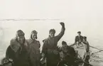 Fotografi från svenska undsättningsexpeditionen 1928. Motiv av en grupp män i en liten båt.