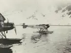 Fotografi från svenska undsättningsexpeditionen 1928. Motiv av två flygbåtar i vattnet nedanfär snötäckt berg i Virgo Bay, 1928.