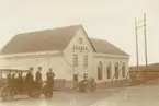 Fotografi från Albin Ahrenbergs resa till Grönland 1929. Motiv av tre män vid bil och hus.