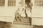 Fotografi från Albin Ahrenbergs resa till Grönland 1929. Motiv av en grupp män och kvinnor på hustrappa.