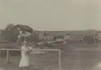 Fotografi från Albin Ahrenbergs resa till Grönland 1929. Motiv av kvinna framför hus på landet.