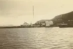 Fotografi från Albin Ahrenbergs resa till Grönland 1929. Motiv av liten hamn, hus och berg.