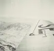 Fotografi från Albin Ahrenbergs resa till Grönland 1929. Vy över snötäckt bergslandskap. Bilden är tagen från flygplan och i förgrunden syns flygplansvinge.