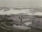 Fotografi från Ahlmannexpeditionen 1931. Motiv av män som bygger hus i öde landskap.