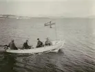 Fotografi från Ahlmannexpeditionen 1931. Motiv av fyra män i liten båt på hav.