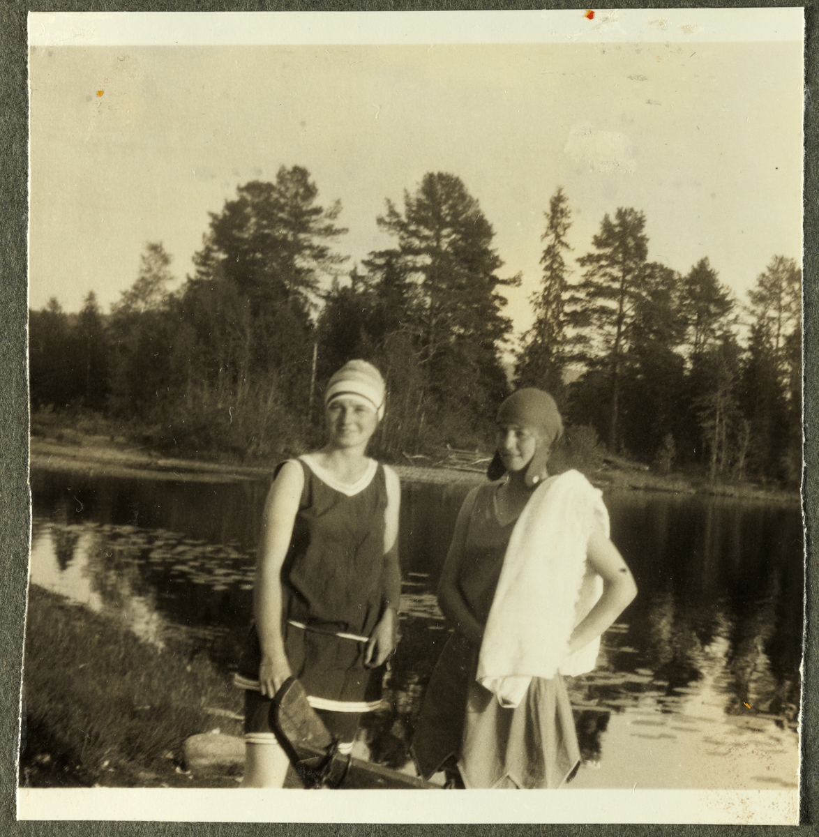 To unge kvinner, antagelig Lucy Egeberg og venninnen Birgit G., gjør seg klar til et bad i innsjøen Malungen i Hedmark. Fotografert 1925.