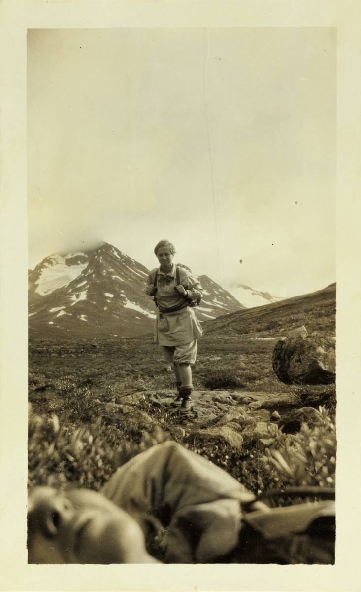 To fjellvandrere på vei til Leirvassbu i Jotunheimen. Stående Mimi Egeberg, liggende i forgrunnen trolig Lucy Egeberg. Fotografert juli 1926.