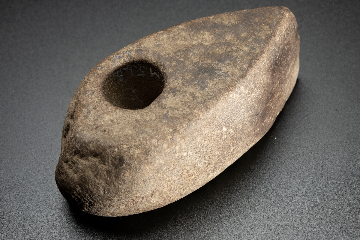 Skafthålsyxa av finkornig bergart (grönsten). Plana ytor. Välslipad. Nackpartiet oregelbundet.