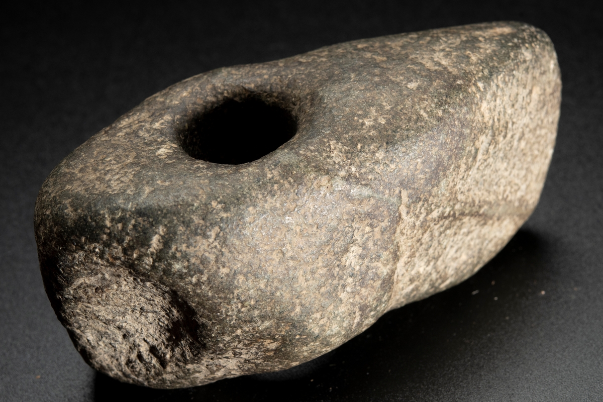 Skafthålsyxa av finkornig grönsten. Oregelbunden. Höga smalsidor.