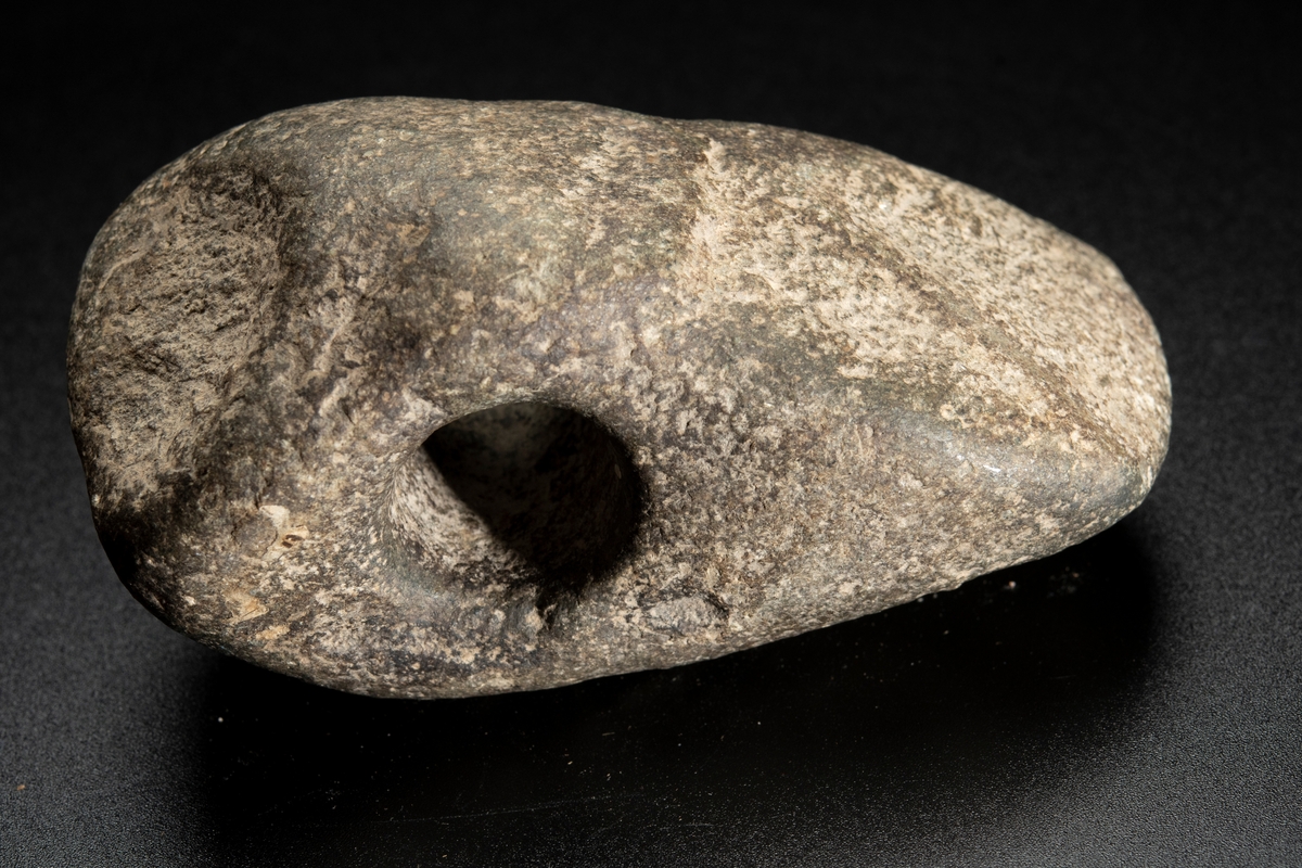 Skafthålsyxa av finkornig grönsten. Oregelbunden. Höga smalsidor.