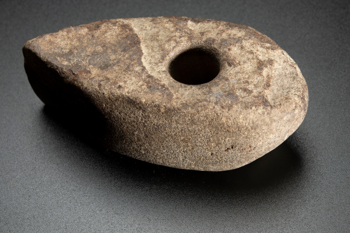 Skafthålsyxa av finkornig bergart (grönsten). Plana ytor. Välslipad. Nackpartiet oregelbundet.