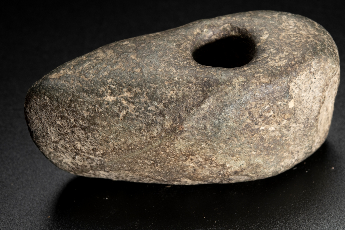 Skafthålsyxa av finkornig grönsten. Oregelbunden. Höga smalsidor.