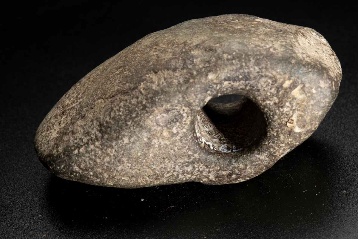 Skafthålsyxa av finkornig grönsten. Oregelbunden. Höga smalsidor.