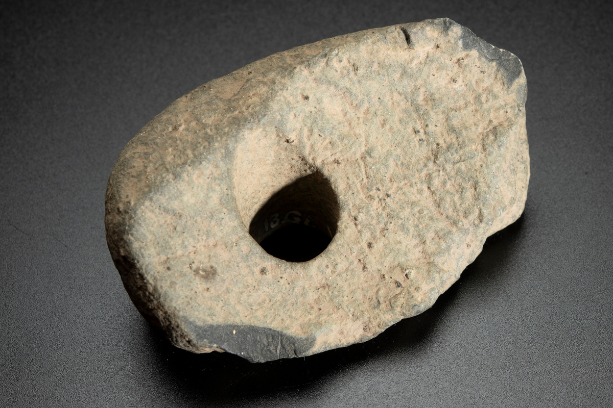 Fragment av skafthålsyxa av grönsten. Yxan skuren i sin längdriktning, mitt itu. Brottytan går diagonalt från undersidan till ovansidan. Obetydligt slipad. Omkring halva yxan är avslagen.