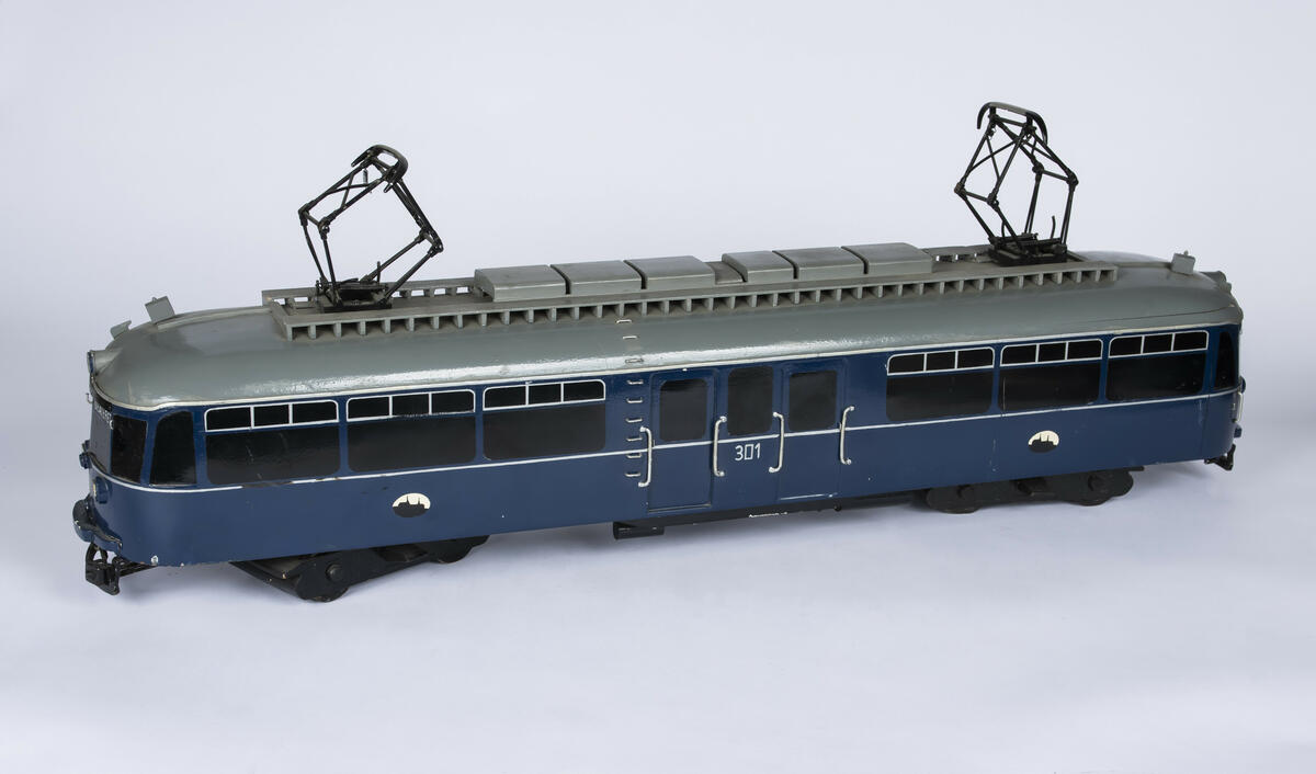 Tremodell i en mørk blå farge, med sorte vinduer og grått tak av forstadsbane fra Bærumsbanen med nr. 301. Modellen har detaljerte utskjæringer og malingsdetaljer som gjør den tro til originalen. På taket er to pantografer til kontaktledningen. 