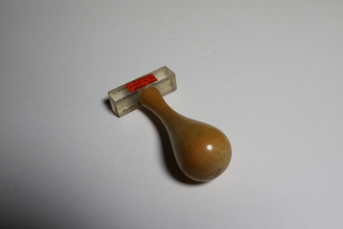 Gummistempel på rektangulært stempelhodet som er gjennomsiktig og man kan da lese hva som står under stempelet. I midten på toppen er håndtaket festet. Håndtaket smalner først svakt inn før det  vider seg ut mot den runde toppen som gir det et pæreformet form.