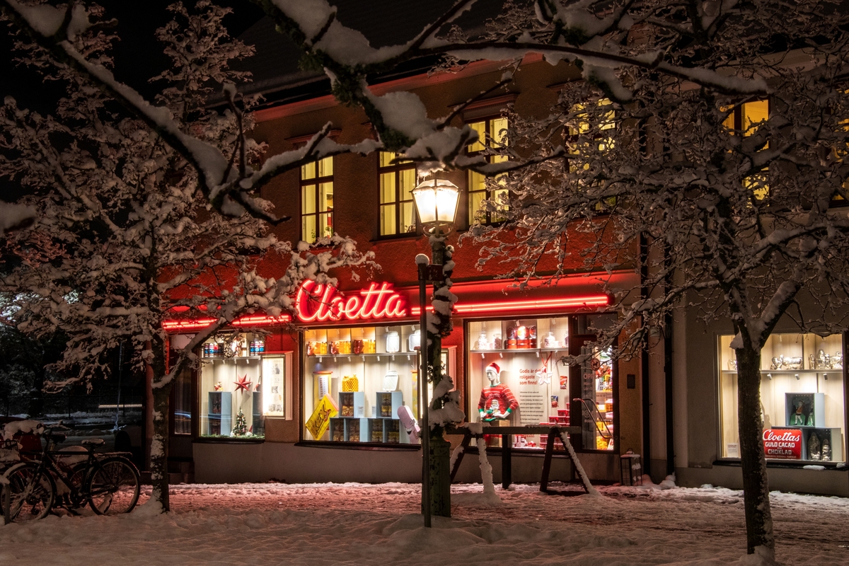 Cloettaboden på Tunnbindaregatan i Gamla Linköping. Man ser upplysta skyltfönster på Cloetta inför julhandeln. Vinter i Friluftsmuseet Gamla Linköping år 2022.