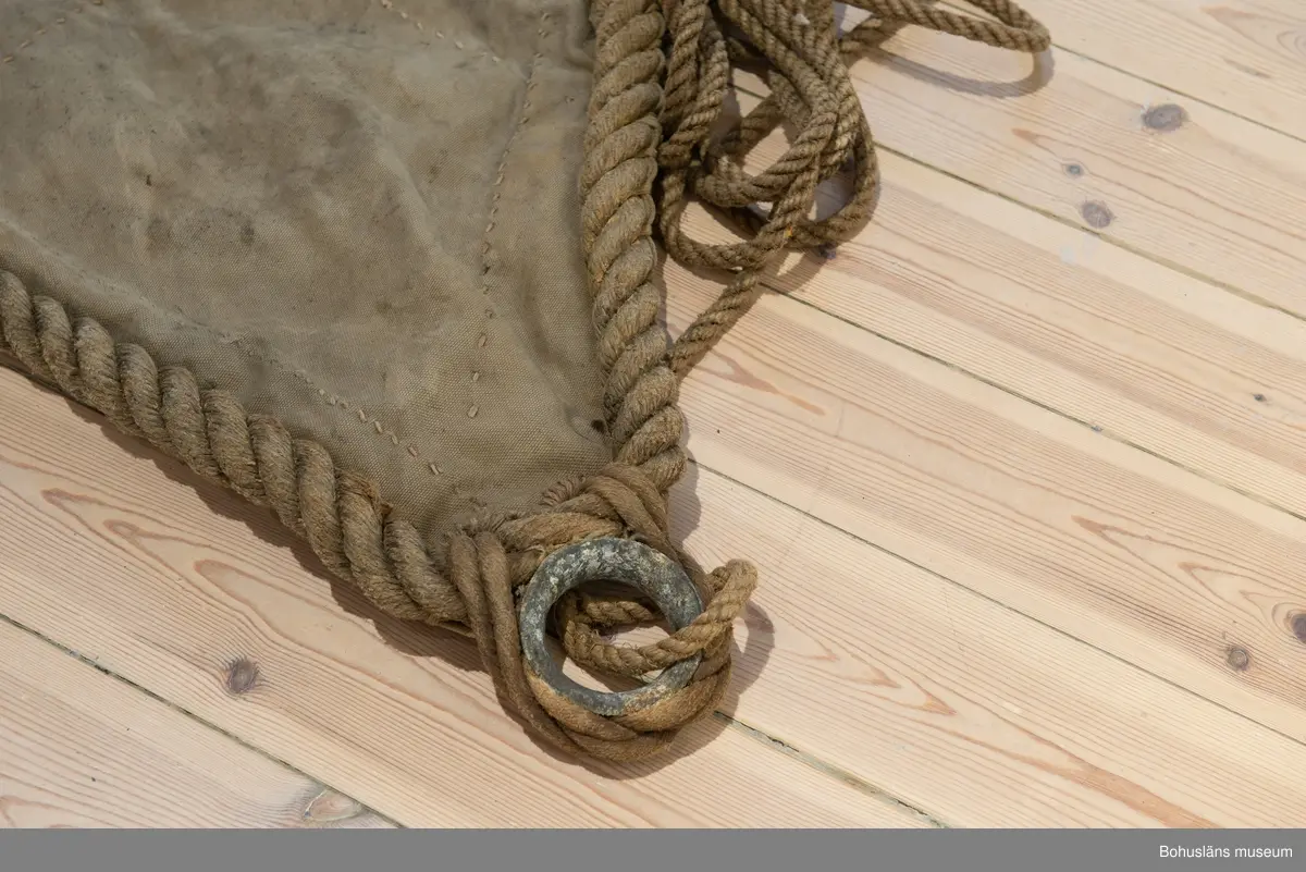 Segel Av kraftig obarkad segelduk av linne. Samtliga sidor - lik - förstärkta med tågvirke. 
Målade beteckningen SD 326 i svart. (Strömstad). 
Seglet är omsytt av ett tidigare storsegel till vanlig fiskebåt, arbetet utfört av segelmakare.