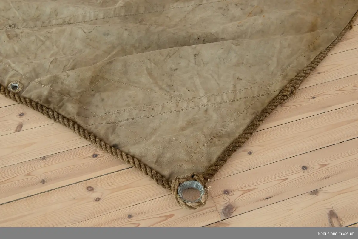 Segel Av kraftig obarkad segelduk av linne. Samtliga sidor - lik - förstärkta med tågvirke. 
Målade beteckningen SD 326 i svart. (Strömstad). 
Seglet är omsytt av ett tidigare storsegel till vanlig fiskebåt, arbetet utfört av segelmakare.