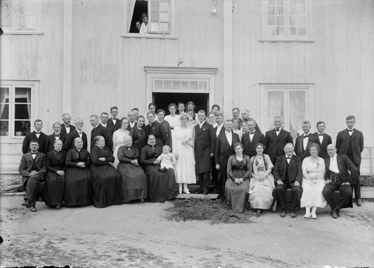 Om bildet er gitt følgende opplysninger: Dette er fra bryllupet til Margit Dahl (f.1895) og Herman Kornelius Bøhmer (f.1887) 8.juni 1920. Bildet tatt på Nedre Dal i Fåberg. Foruten brudeparet er noen få identifisert, sittende foran fra venstre: Iver Rustad (f.1869), Agnethe Petronelle Jørstad (1862-1947), nummer 6 med et lite barn på fanget brudens mor Rønnaug Dahl født Torgersrud (1865-1948). Stående helt til høyre brudens bror Erik Dahl, til venstre for han Andreas Nøss (?). Dama som står rett bak og til venstre for brudgommen er Kari Jørstad (1889-1942), senere Brateng. Dama som står rett under venstre dørstolpe er brudens søster Agnes Dahl, gift Sollien. Stående bak fra venstre nummer tre lærer og kirkesanger Peter Ingemar Schieflo (1866-1956), deretter Arne A. Jørstad (1861-1942) og nummer seks Andreas A. Jørstad (1891-1969). Ifølge Anne Marit Sollien, barnebarn av brudens søster Agnes så utvandret Margit og Herman til Canada i 1929 med to barn, Kåre og Ragnhild. De bodde i Bawlf, nær Camrose i Alberta.  Kåre var 6 år gammel da de utvandret, og tok over farmen etter foreldrene. Han døde 99 år gammel og pratet "kav Fåbæring" da de hadde nordmenn på besøk, forteller Anne Marit Sollien. Lengst til venstre i andre rekke: Knut Stende (1889-1984). Nr fem fra venstre i andre rekke, i lys kjole: Elisabeth Stende (1889-1975, født Torgersrud, gift med Knut Stende). Nr fire fra høyre i andre rekke : Ole Torgersrud (1851-1937), far til Elisabeth.