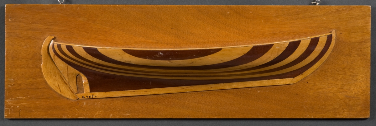 Halvmodell av fiskebåt av Öresundstyp. Byggd i block av trä, visande styrbords sida. Vertikala skikt i omväxlande björk och mahogny, fernissad. Monterad på fernissad platta av kryssfanér.