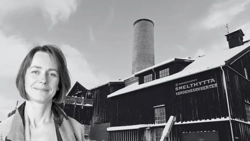 Bildet viser et utsnitt av museumsdirektør Tone Rygg foran museumsbygningen Smelthytta. Bildet er i svart hvitt.
