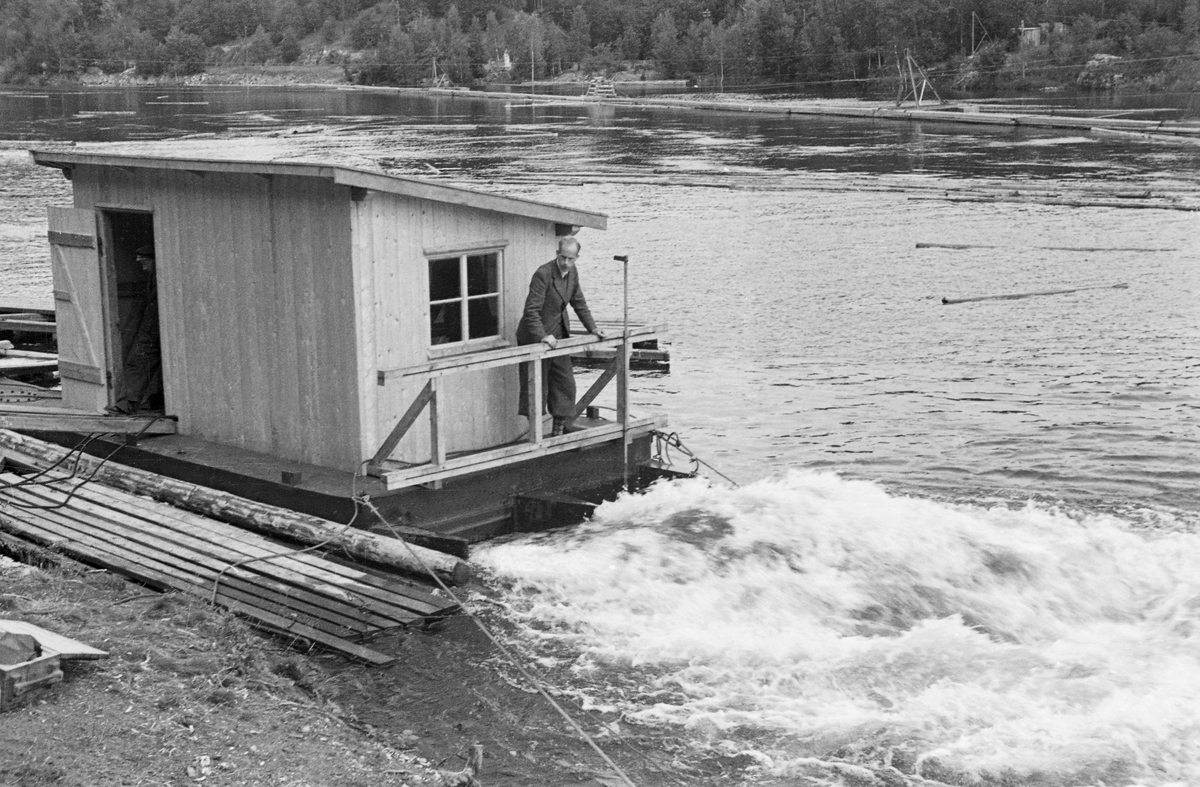 Fra forsøk med strømdannerapparat i dammen ved Kykkelsrud kraftstasjon i 1942. Da dette fotografiet ble tatt sto en mann, ingeniør Mohn, på flåten apparatet var montert på. Vannet mellom pontongene var kvitskummende og tydelig i bevegelse. Det som satte vannet i bevegelse var sannsynligvis en diger, roterende propell som befant seg i vannet, og som antakelig ble drevet av en motor som befant seg i det nevnte huset, via kjeder. Flåten ble holdt i posisjon ved hjelp av vaiere, som formodentlig var forankret i fastpunkter på land. Poenget var at propellen skulle skape en ønsket bevegelse i vannet. Her ved Kykkelsrud, hvor det var en kraftstasjon, dreide det seg antakelig om å skape strømninger som skulle bevege fløtingsvirket mot den tømmerrenna som skulle ta stokkene forbi kraftverksdammen. Det dreide seg med andre ord om et tiltak som skulle øke ekspedisjonshastigheten ved tømmerrenna uten å øke forbruket av vann, noe som jo ville ha gått på bekostning av kraftproduksjonen. Vi vet foreløpig lite om akkurat dette forsøket, men etter krigen markedsførte Olsen & Thorsen mek. verksted, ofte kortkortet til «OTHO», slike strømdannere med motorer som kunne yte fra 10 til 60 hestekrefter. Firmaet hevdet at disse maskinene kunne generere strøm så langt som 60 til 80 meter fra det stedet hvor den roterende propellen ble montert. Fløtingsfunksjonærene erfarte nok at vikrkningen ikke var fullt så vidtrekkende som produsenten forespeilte dem. Dette apparatet var sannsynligvis produsert ved Fredrikstad mek. Verksted på Kråkerøy (jfr. SJF.1989-04524 - SJF.1989-04527). Firmaet Olsen & Thorsen mek. verksted markedsførte et liknende produkt overfor virksomheter som hadde behov for mudring. 

Dette er en montasje av tre bilder -  hentet fra et av Glomma fellesfløtingsforenings album, der man, i mangel av vidvinkelobjektiv, hadde forsøkt å montere tre fotografier, tatt med korte intervaller, ved sida av hverandre.