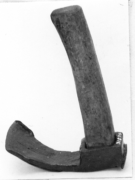 Tväryxa så kallad Täxla av järn med handtag av bok. Eggen något konvex. Huvudets baksida en oval, avsedd att slå i spik med. 
Längd (täxlan) 15 cm. Längd (hantag) 21,5 cm. 
Bredd (täxla) 6,5 cm, Bredd (handtag) 3,6 cm.