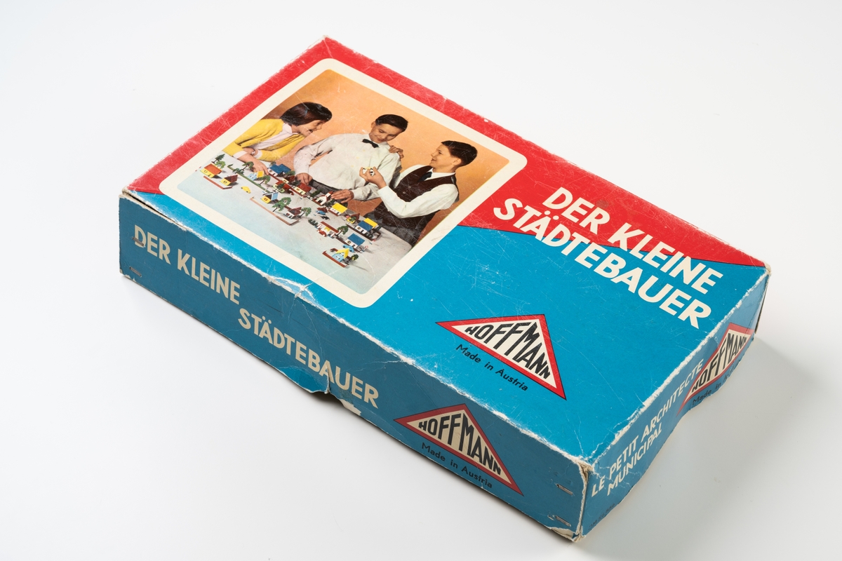 Byggsats "Der kleine Städtebauer" med originalkartong innehållande delar för bygge av bebyggelsemiljö. Innehållet består av små byggnader, staket, träd, trafikmärken samt troligen även sekundärt nedlagda delar. Kartonglocket har tryckt färgfotografi av lekande barn och text. Kartonglocket är trasigt i två hörn.

Innehåll:
1. Bostadshus av plast, 8 st
2. Kyrka av plast, 1 st
3. Bensinstation av plast, 1 st
4. Staket av plast, 9 st
5. Plank av plast, 3 st, sekundära?
6. Lövträd av plast, 4 st
7. Barrträd av plast, 6 st
8. Vägmärken av plast (låga, vita) 5 st
9. Vägmärken av plast (höga, gula) 14 st, sekundära?
10. Vägmärken av plåt, "Made in Japan", 4 st, sekundära?
11. Bilar av plåt, "Made in Japan", sekundära?
12. Flygplan av plast, "Kalaspuffar", 1 st, sekundär
13. Fyra hjul av plast, varav två på axel, vilka förmodligen tillhört ursprungliga plastbilar i lådan

Se vidare Historik