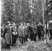 Några män iklädda regnrockar står uppställda för fotografering. De befinner sig i en skog.