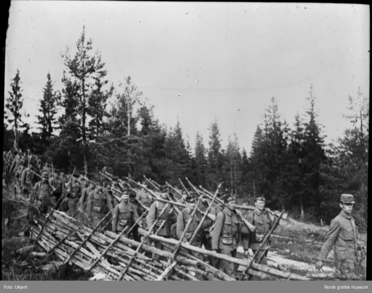 Soldater på vei langs en skigard. De har uniform og geværet over skuldra, antageligvis i området mellom Skotterud og Kongsvinger.