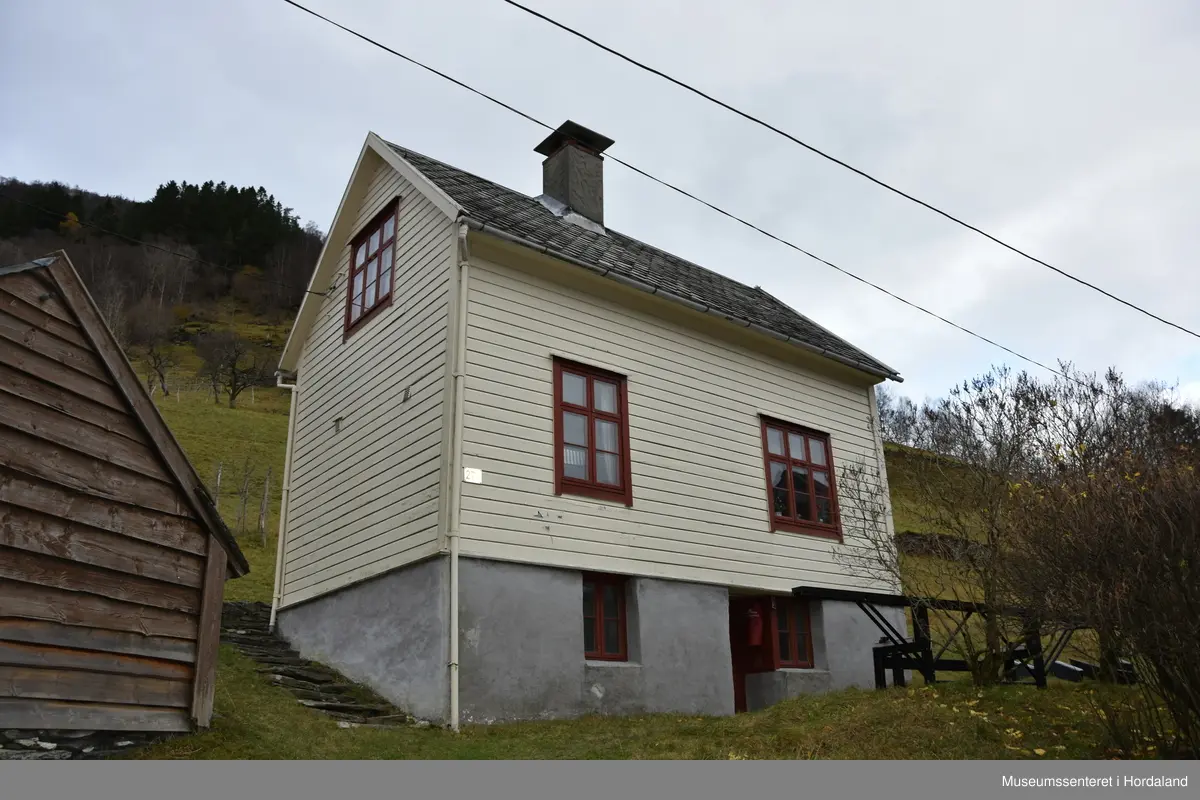 Halvannan etsjes hus i maskinlaft. Taket tekt med dråpeskifer. Liggande kledning på veggane. Huset har kjellar i naturstein. Pussa grunnmur.