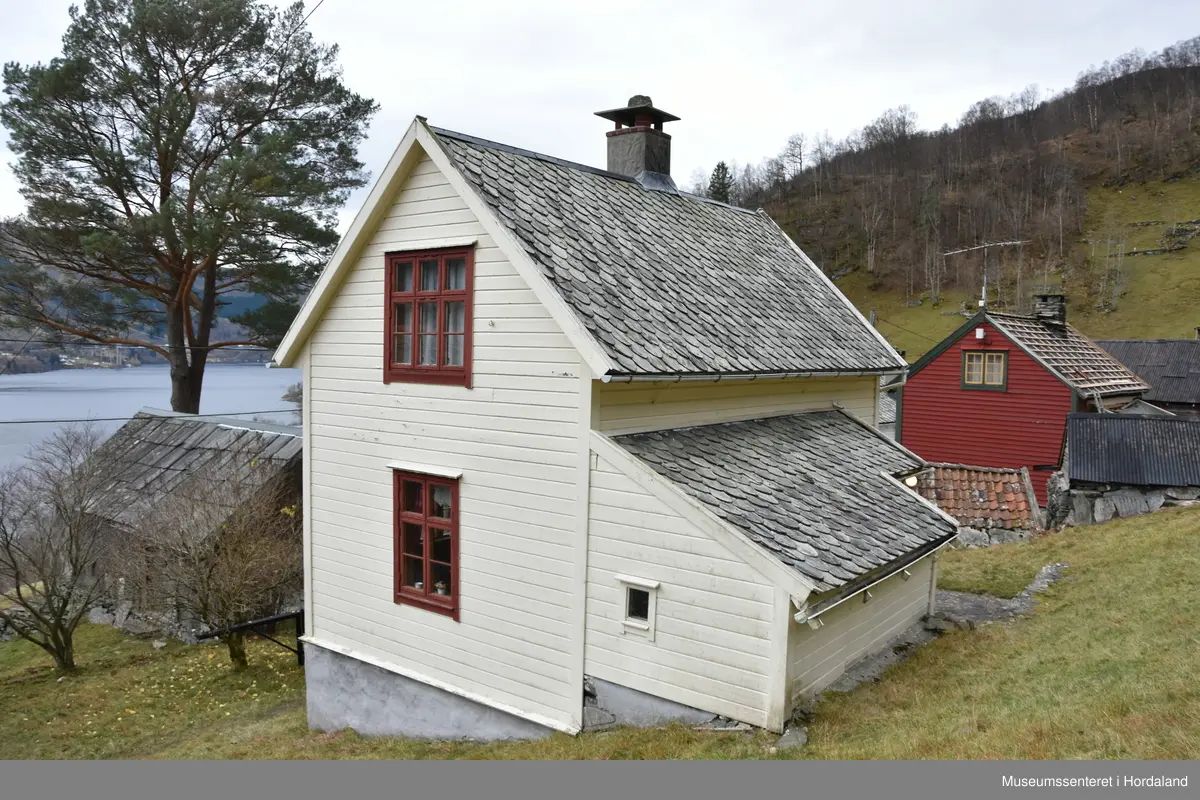 Halvannan etsjes hus i maskinlaft. Taket tekt med dråpeskifer. Liggande kledning på veggane. Huset har kjellar i naturstein. Pussa grunnmur.