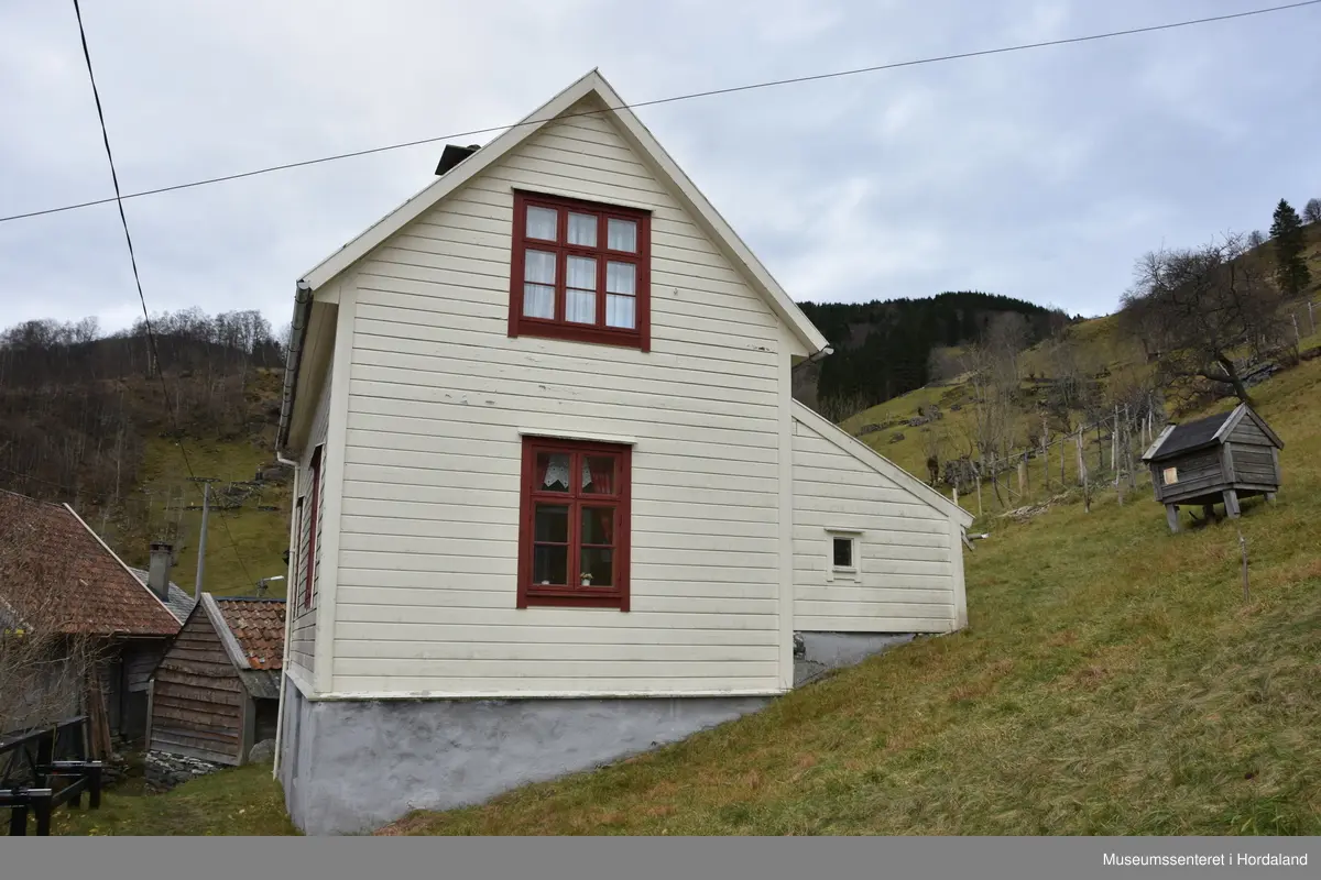 Halvannan etsjes hus i maskinlaft. Taket tekt med dråpeskifer. Liggande kledning på veggane. Huset har kjellar i naturstein. Pussa grunnmur.