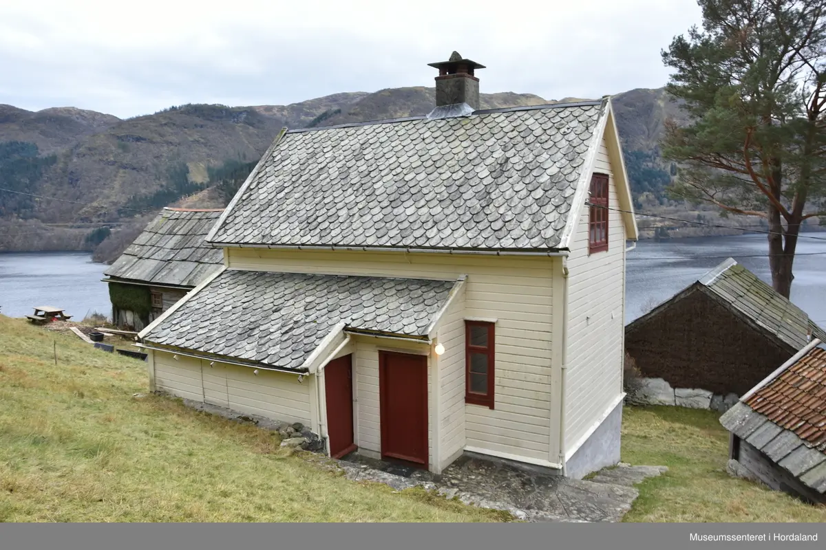 Halvannan etsjes hus i maskinlaft. Taket tekt med dråpeskifer. Liggande kledning på veggane. Huset har kjellar i naturstein. Pussa grunnmur.