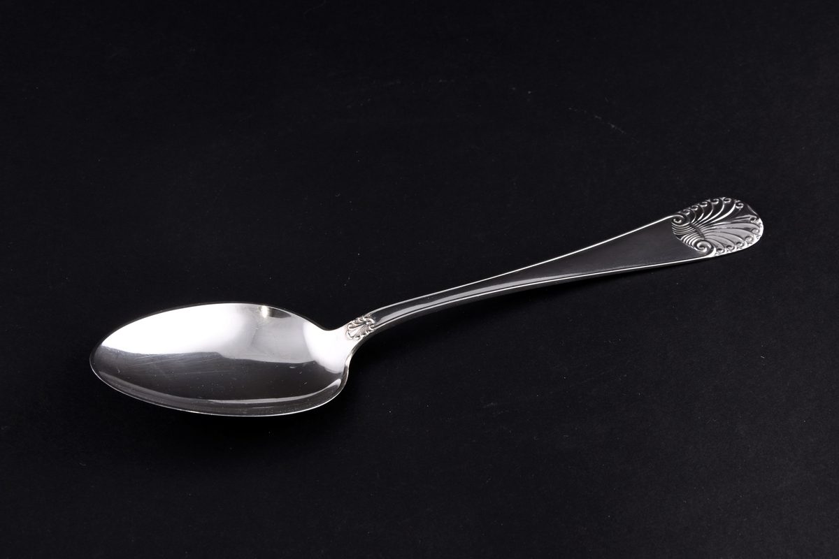 Sølvskje med mønster på enden av skaftet og ved overgang til skje.