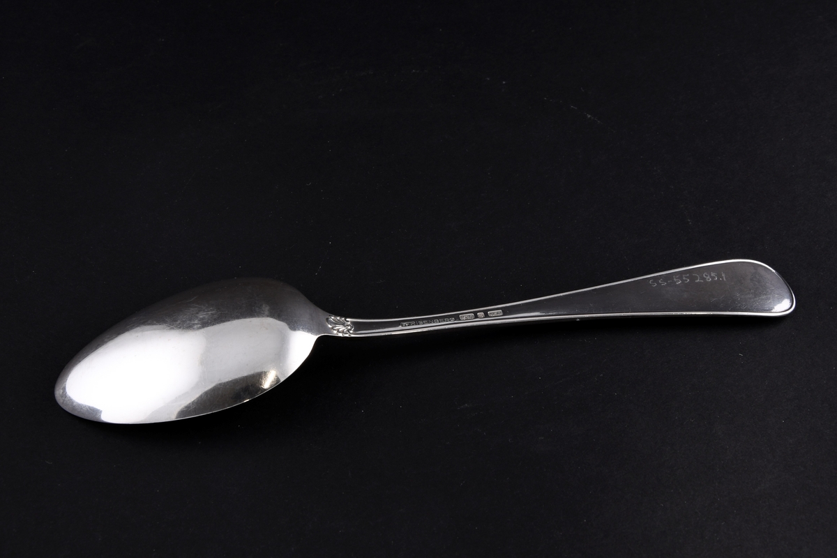 Sølvskje med mønster på enden av skaftet og ved overgang til skje.