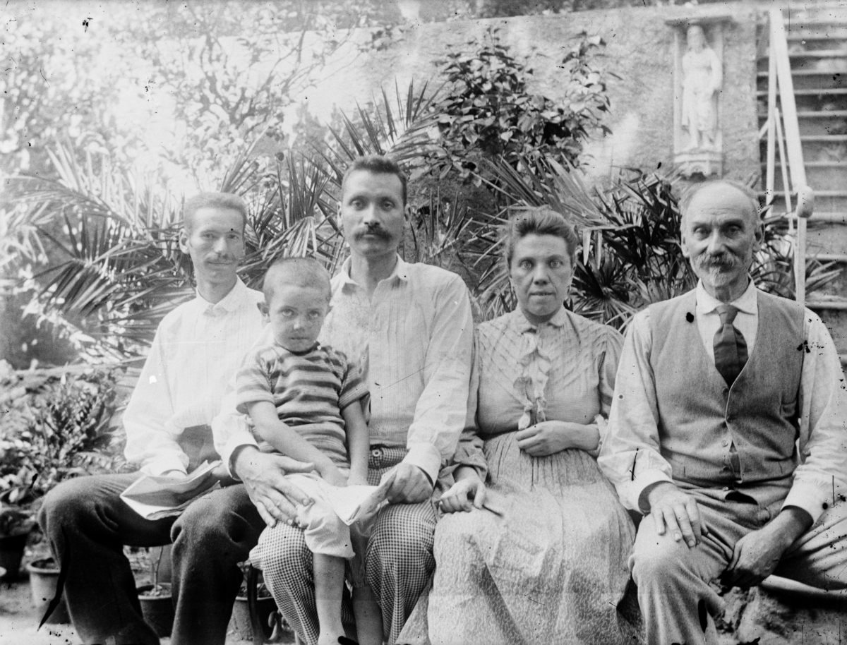 Gruppebilde av fem personer med ett barn, ei kvinne og tre menn. I bakgrunnen palmeblader