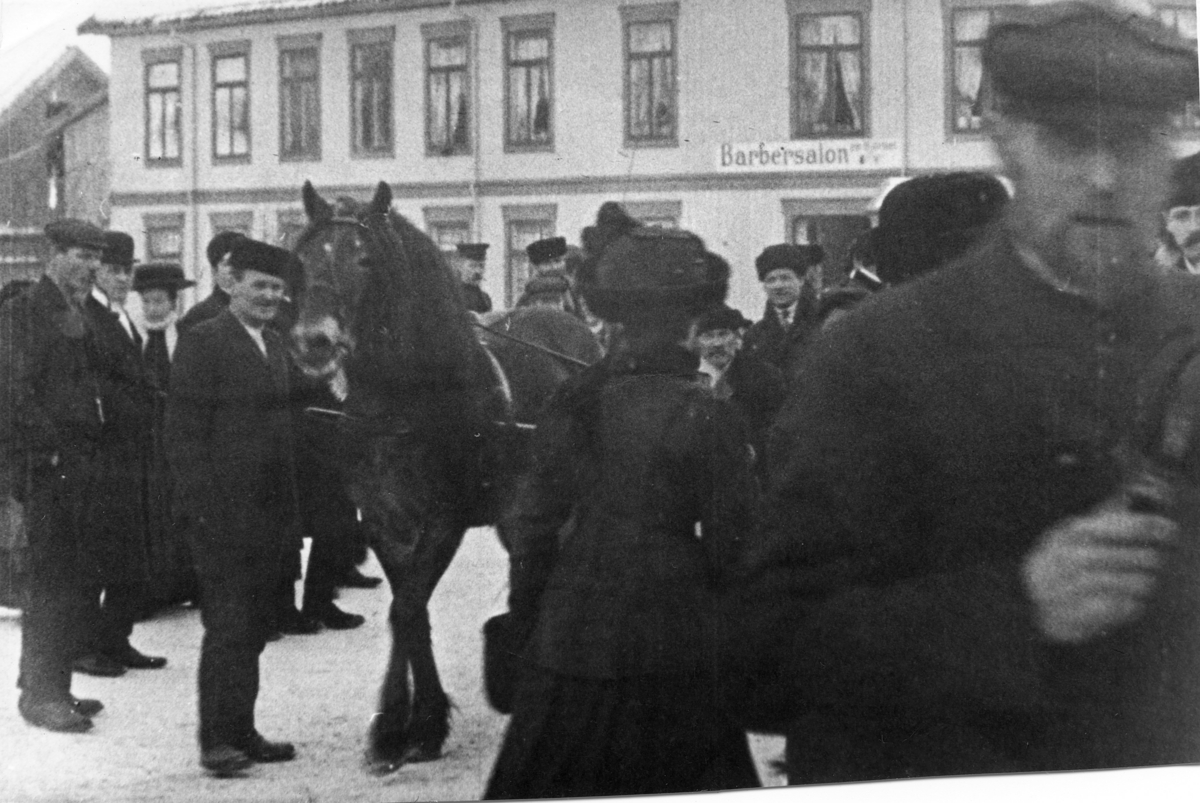 Stillbilde fra Albert Hougners film fra Storgata, Lillehammer 1912. Fra Mesnabrua med mennesker og hester. I bakgrunnen Storgata 86 med barbersalonen til C Syversen