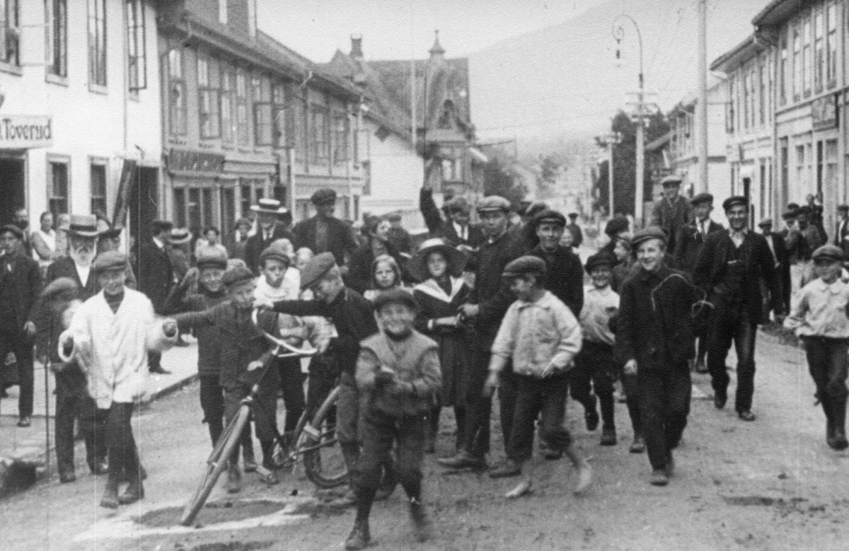 Stillbilde fra Albert Hougners film fra Storgata, Lillehammer 1912. Storgata nord for Lilletorget, mange barn og voksne i gata. Til venstre Toveruds forretning i Storgata 96. Scene fra Albert Hougners film "Storgaden 1912".